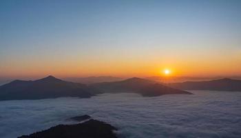 Silhouettes through of  beautiful landscape on the mountains at sunrise. Spectacular view in foggy valley covered forest under morning sky. photo