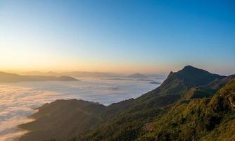 Beautiful landscape on the mountains at sunrise. Spectacular view in foggy valley covered forest under morning sky. photo