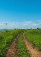 Landscape view of countryside dirt road path crosses the hills with blue sky background. photo