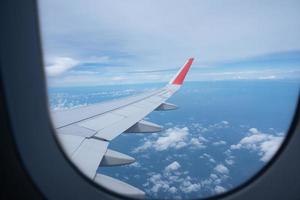 Airplane wing flying above the sky with white clouds. View from aircraft window. flying and traveling concept. photo