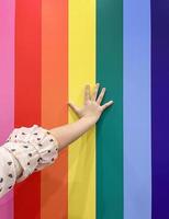 Child hand put on rainbow LGBT flag background. concept for LGBTQ equality movement community. photo