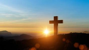 siluetas de cristiano cruzar símbolo en parte superior montaña a amanecer cielo antecedentes. concepto de crucifixión de Jesús Cristo. foto