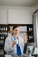 Attractive female doctor talking while explaining medical treatment to patient through a video call with laptop in office photo