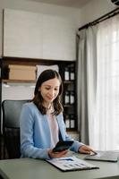 Beautiful business woman typing laptop and tablet Placed at the table at the modern office photo