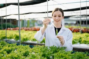 Researcher in white uniform are checking with ph strips in hydroponic farm and pH level scale graphic, science laboratory greenhouse concept. photo