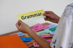 Closeup student's hands  hold English Grammar word card. Concept, education, learning, studying language. Education. Reading and memorizing strategy of learning process for kid. Practice makes perfect photo