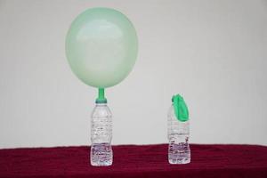 Science experiment , green inflated balloons and flat balloon  on top of transparent test bottles. Concept, science experiment about reaction of chemical substance, vinegar and baking soda. photo