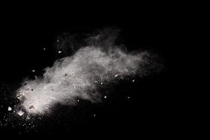 Split debris of  stone exploding with white powder against black background. photo