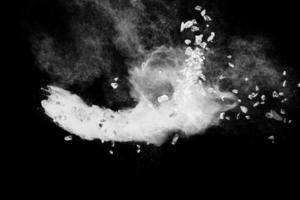 Split debris of  stone exploding with white powder against black background. photo
