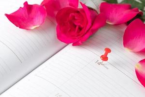 calendario san valentin día rosado alfiler y rojo rosas en calendario cuaderno. foto