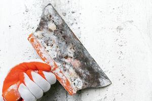 Hand of plasterer holds an old putty knife and scrapes concrete interior wall, removes old plaster photo