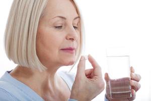 medicine, health care and people concept, close up of middle aged woman taking in pill photo