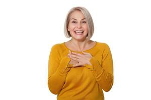 Middle aged blonde emotionally posing in a studio. Happy woman in yellow bright sweater on white background photo