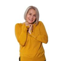 Attractive Middle Aged Woman expresses embarrassment and shame, confusion and insecurity. Woman presses her hands to her neck and feels awkward. Woman in bright clothes posing on white background photo