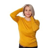 Middle aged blonde emotionally posing in a studio. Happy woman in yellow bright sweater on white background photo