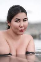 retrato de más Talla mujer con grande pecho baños y relajación en agua de al aire libre piscina a spa foto