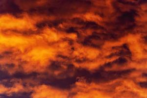 Golden clouds at sunset floating across violet and purple thunderclouds in sky photo