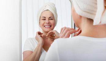 Forty years old woman looking at wrinkles in mirror. Plastic surgery and collagen injections. Makeup. Macro face. Selective focus on the face. photo