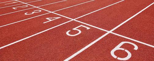 Red running track at stadium with lane numbers photo