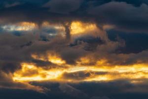 hermosa dramático nubes en cielo iluminado por rayos de Dom a puesta de sol a cambio clima. vistoso verano Cloudscape resumen antecedentes foto