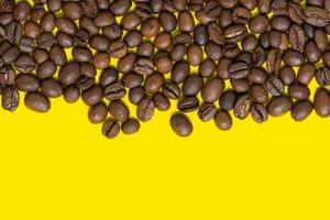 Brown coffee beans on yellow background. Top horizontal location objects, copy space for text at bottom. Flat lay, close-up view of coffee still life photo