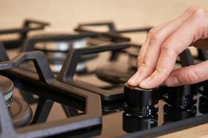 Female hand use gas stove control panel photo