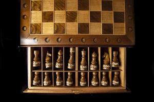 Dark chess pieces lie in a box. A puzzle game with tricky combinations that requires planning and thinking. photo