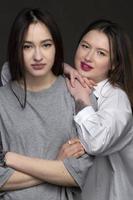 Two beautiful girls-friends on a dark background. photo