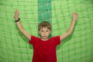 A little boy in the gym stands near the football net. photo