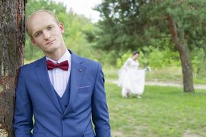 Sad groom of European appearance and the bride blurred in the background. photo