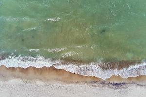 Coastline with blue sea waves and sand beach, top view photo