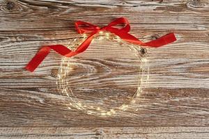 Circle frame made of lighting garland on wooden background photo