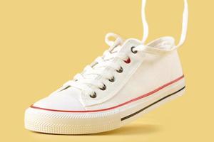 White casual sneakers on yellow background, creative minimalism photo