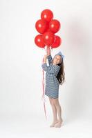 Girl holding large bunch red balloons in hands, smiling and looking at camera on white background photo