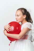Portrait of girl hugging red balloon with both hands, put chin on ball, looking to side on white photo
