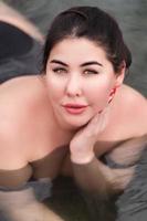 Portrait of brunette xxl young woman in black swimsuit relaxation in pool at spa, hot springs resort photo