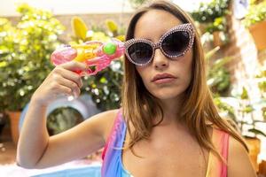 A pretty woman in bikini with a water pistol in a paddling pool photo