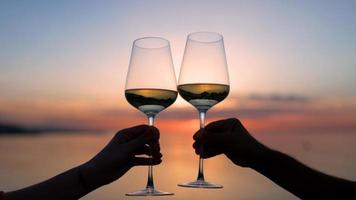 Two hands making a cheers with wine glass against sparkling sea and sky at sunset photo