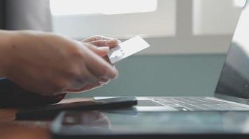 mãos segurando um cartão de crédito e usando o laptop. compras online video