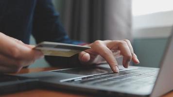 mãos segurando um cartão de crédito e usando o laptop. compras online video