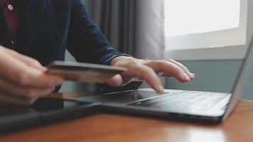 mãos segurando um cartão de crédito e usando o laptop. compras online video