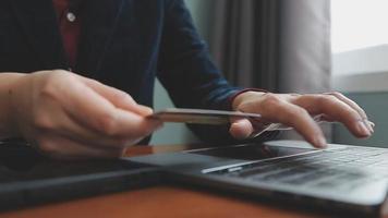 mãos segurando um cartão de crédito e usando o laptop. compras online video