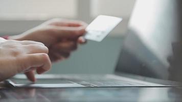 mãos segurando um cartão de crédito e usando o laptop. compras online video