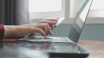 mãos segurando um cartão de crédito e usando o laptop. compras online video