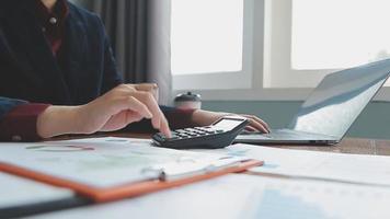 Teamwork of asian business people discussing and calculating with calculator on evaluation data in conference room. with the growth and pointing to the chart graph financial account. video