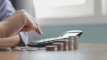 Businessman hand pressing calculator putting coins on pile saving savings for retirement future video