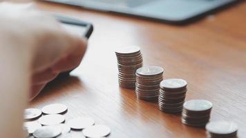 Businessman hand pressing calculator putting coins on pile saving video