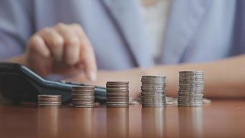 Businessman hand pressing calculator putting coins on pile saving video