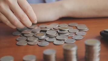 Businessman hand pressing calculator putting coins on pile saving video