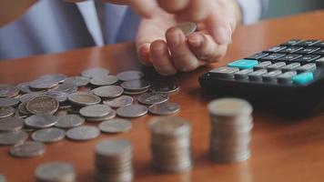 Businessman hand pressing calculator putting coins on pile saving video